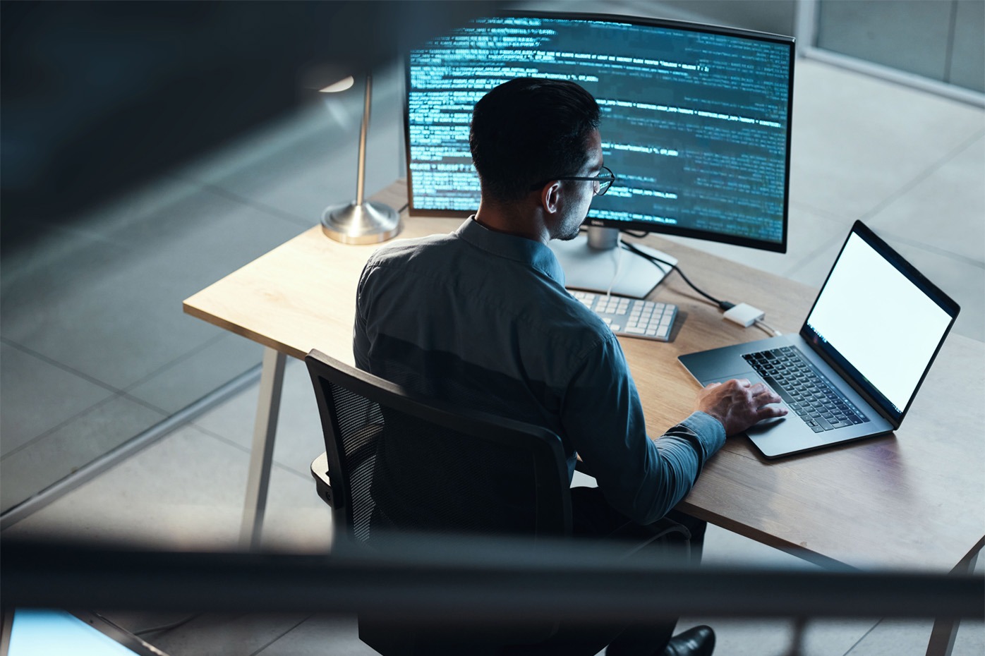 A man sitting at a desk with computer monitors displaying code