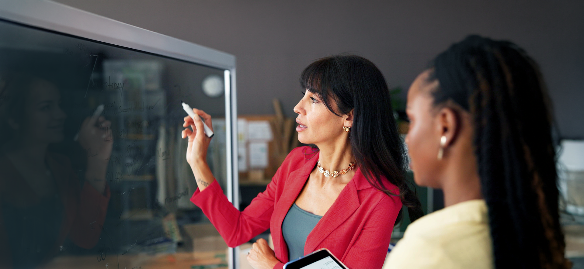 Two women brainstorming using a glass board