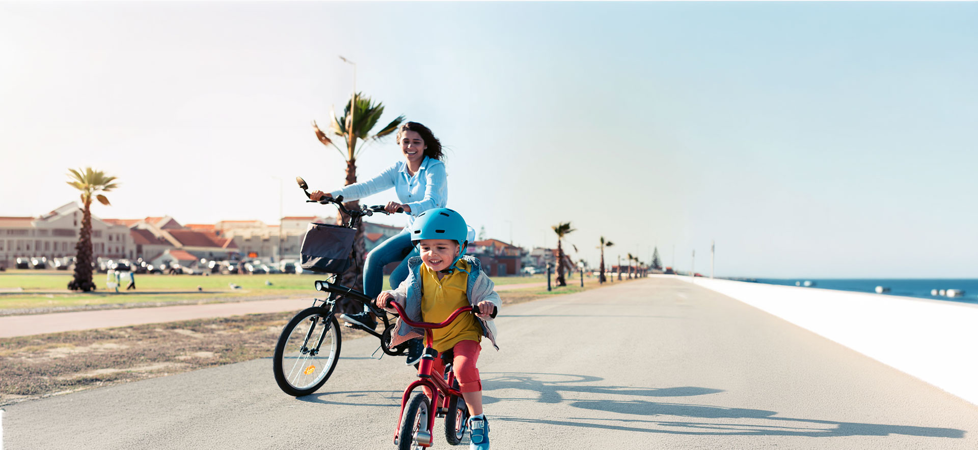 Mother and son riding bicycles on a flat waterfront trail
