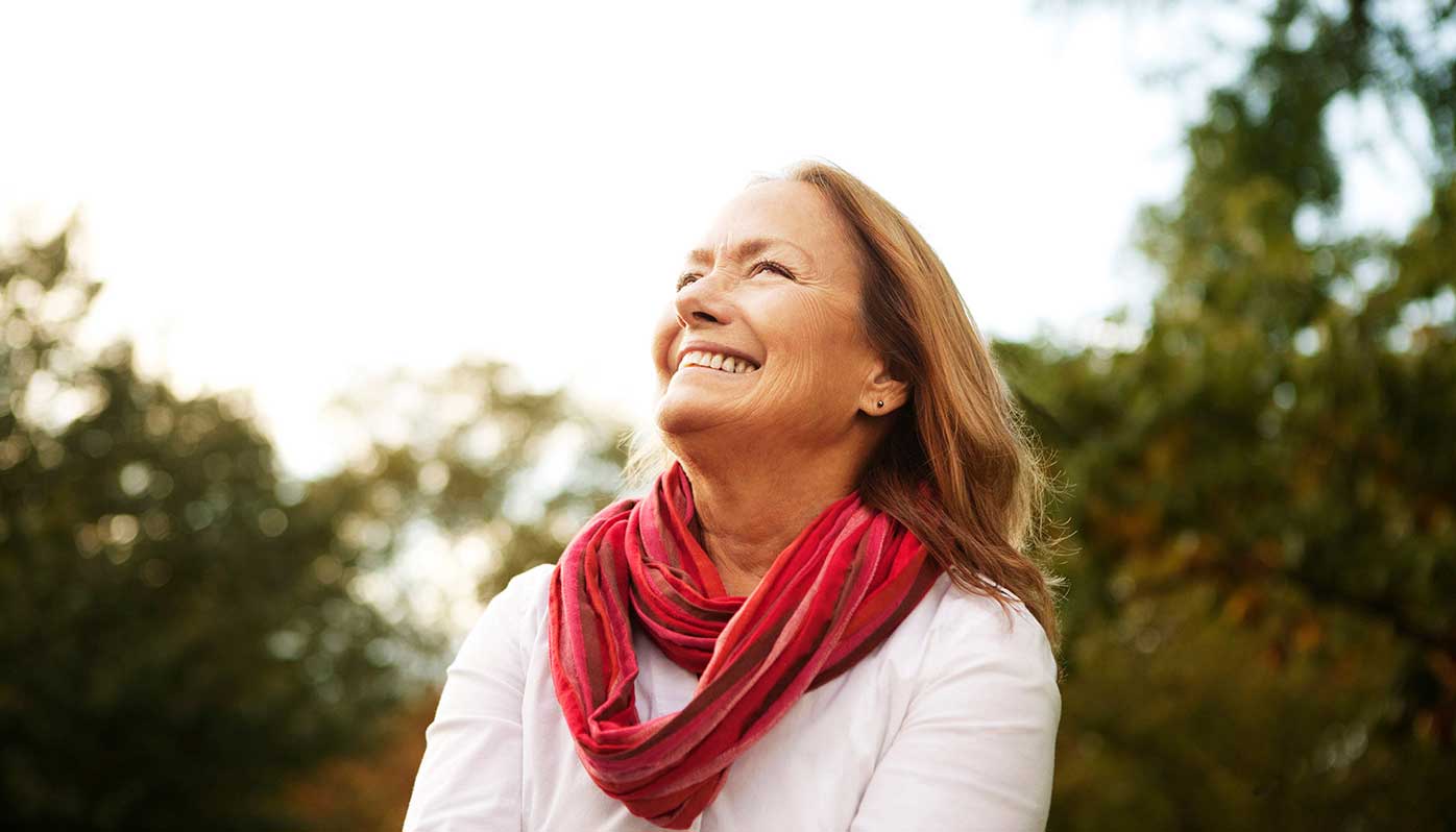 A retired woman gazes into the distance on a walk.