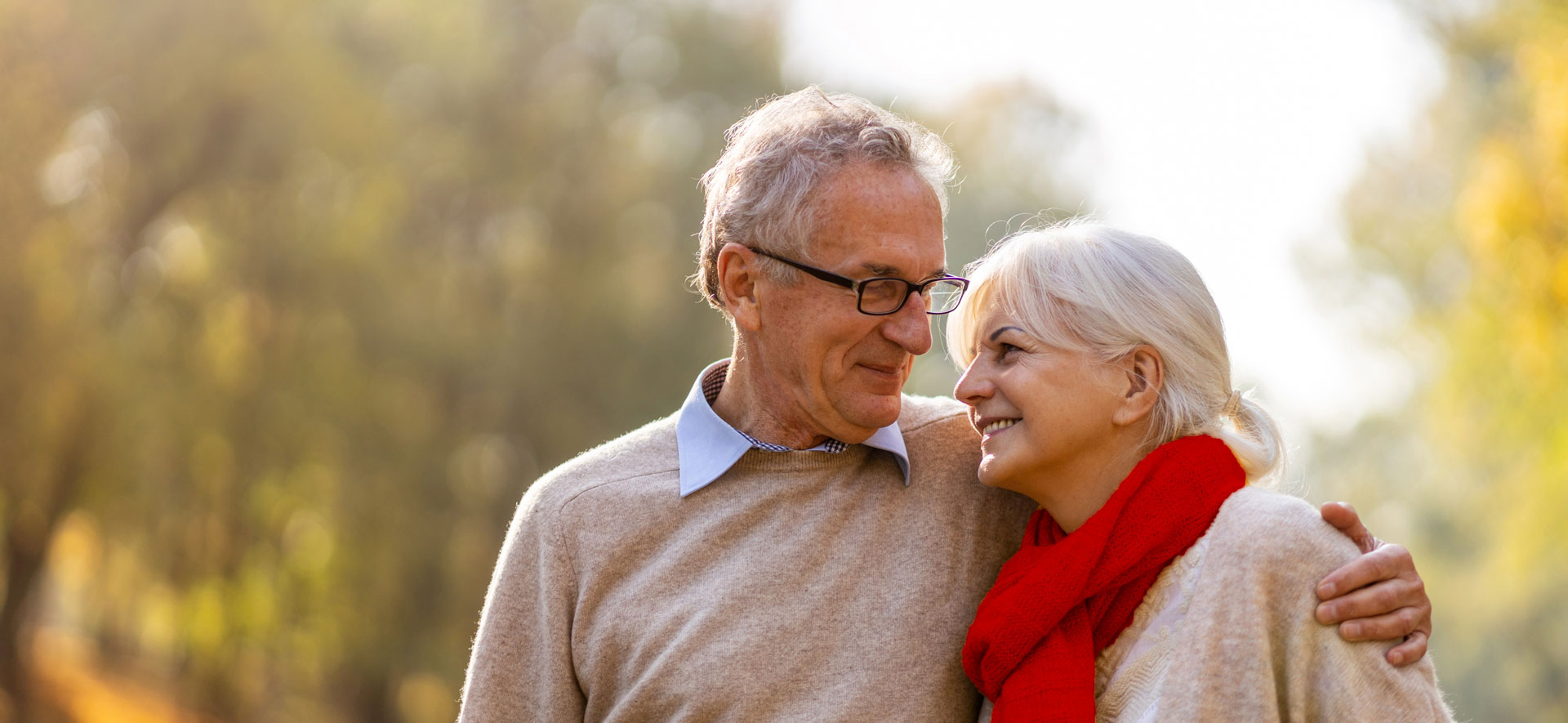 A happy retired couple strolls together through a fall scene