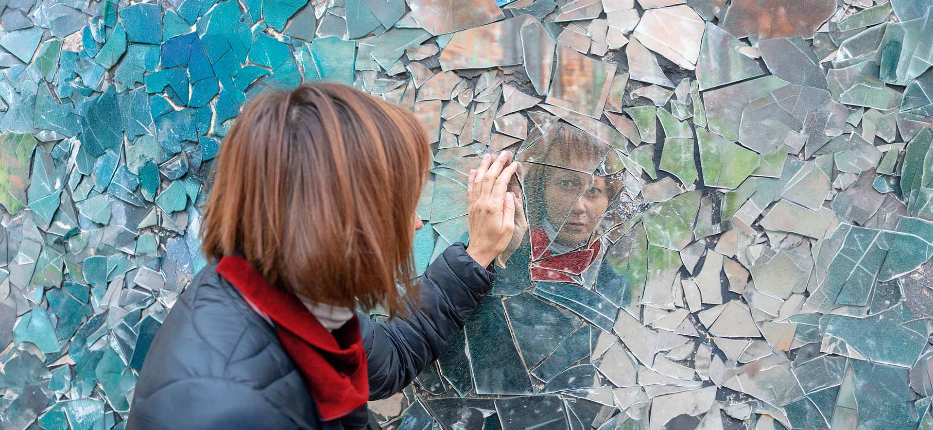 Woman looking in shattered mirror