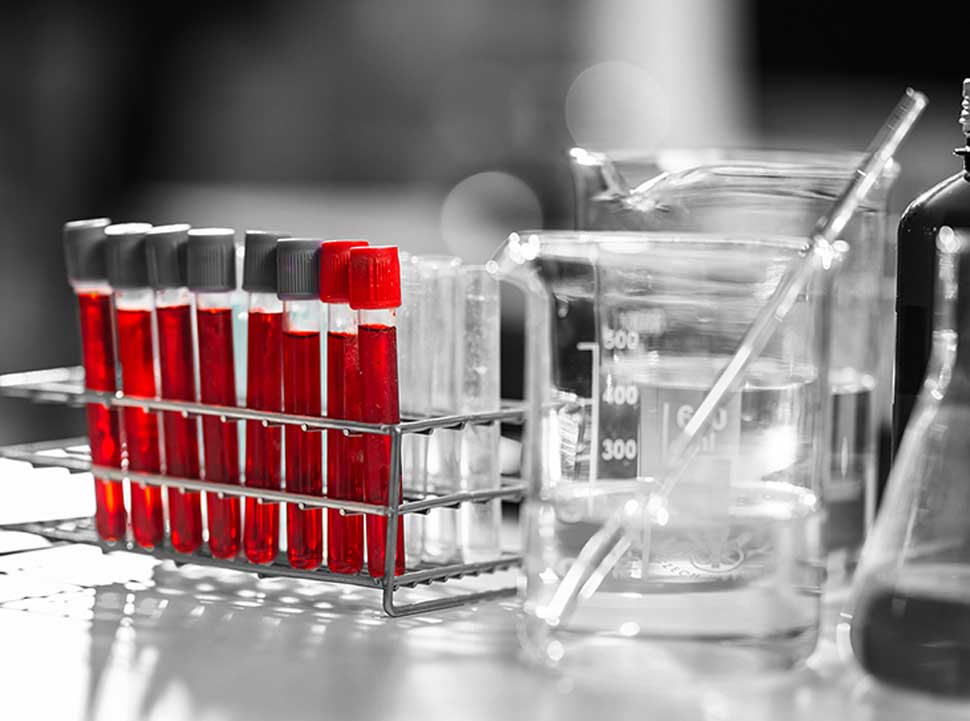 A list of test tubes glow with red liquid on a lab bench