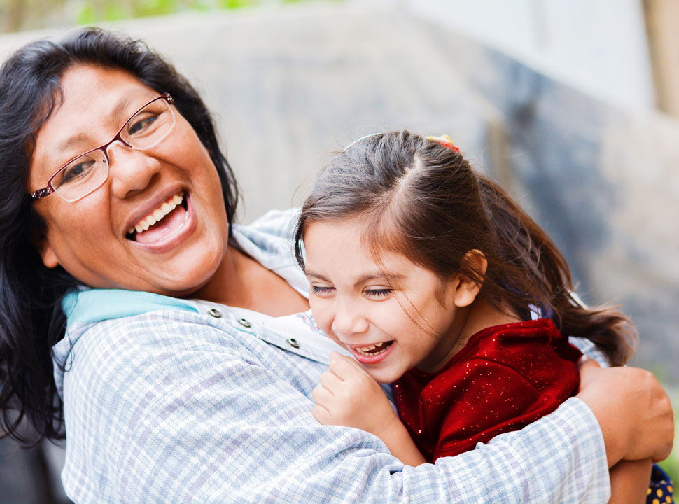 A mother joyfully laughs, hugging her daughter