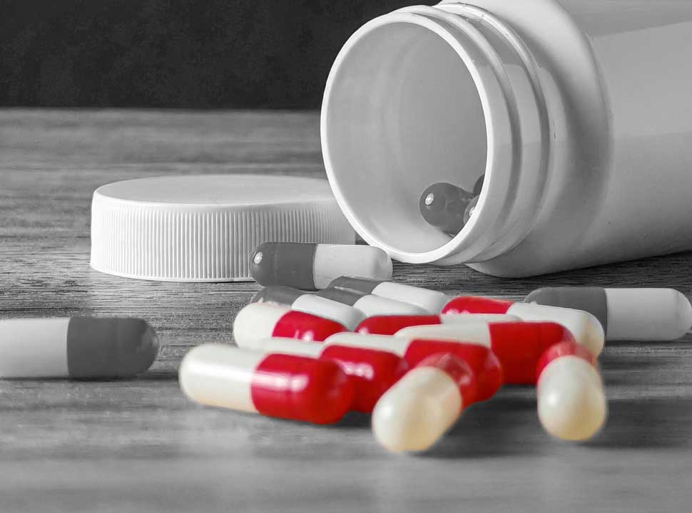 Opioid pills spill from an open container