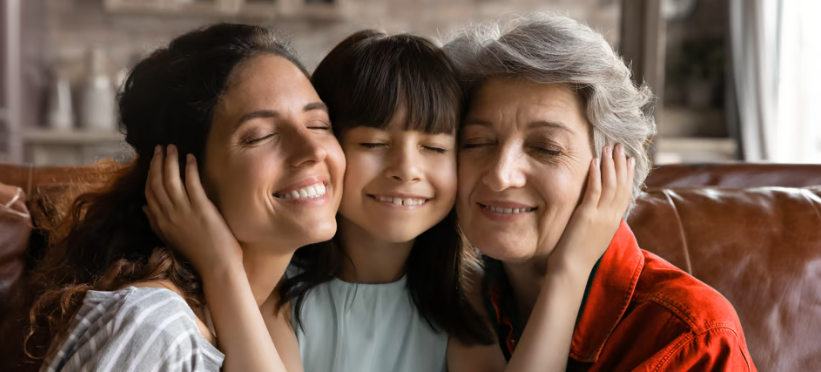 Three generations of women hug and smile.