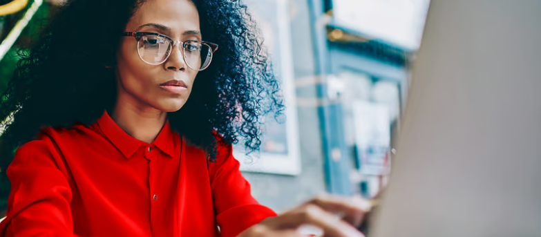 A professional in red focused at her screen — the disciplined analysis behind a de-risking strategy.