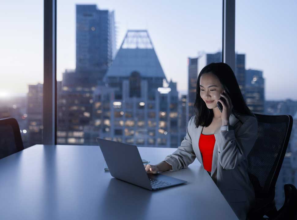 A figure in red works above a city at dusk — individual focus at the scale of a cross-market transaction