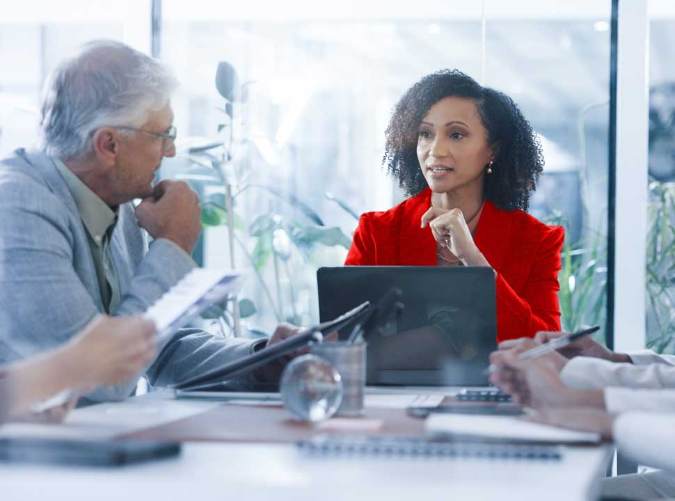 In a room of measured attention, the one voice in red holds the table — the convergence a landmark transaction demands.