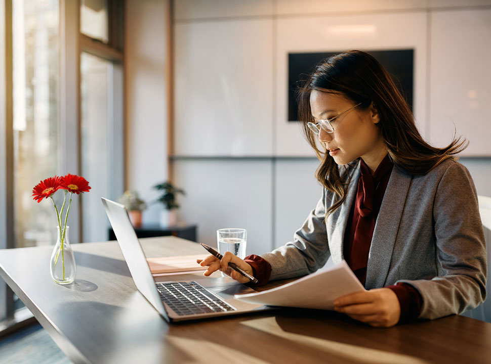 A woman gazes thoughtfully at a claims application on her computer