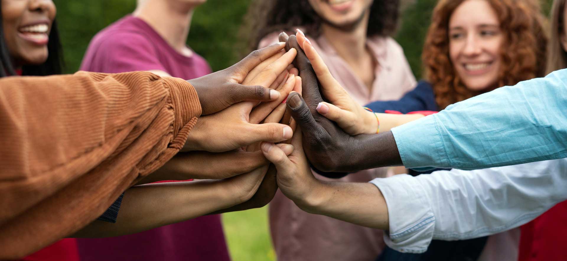 A diverse group clasps hands to showcase teamwork
