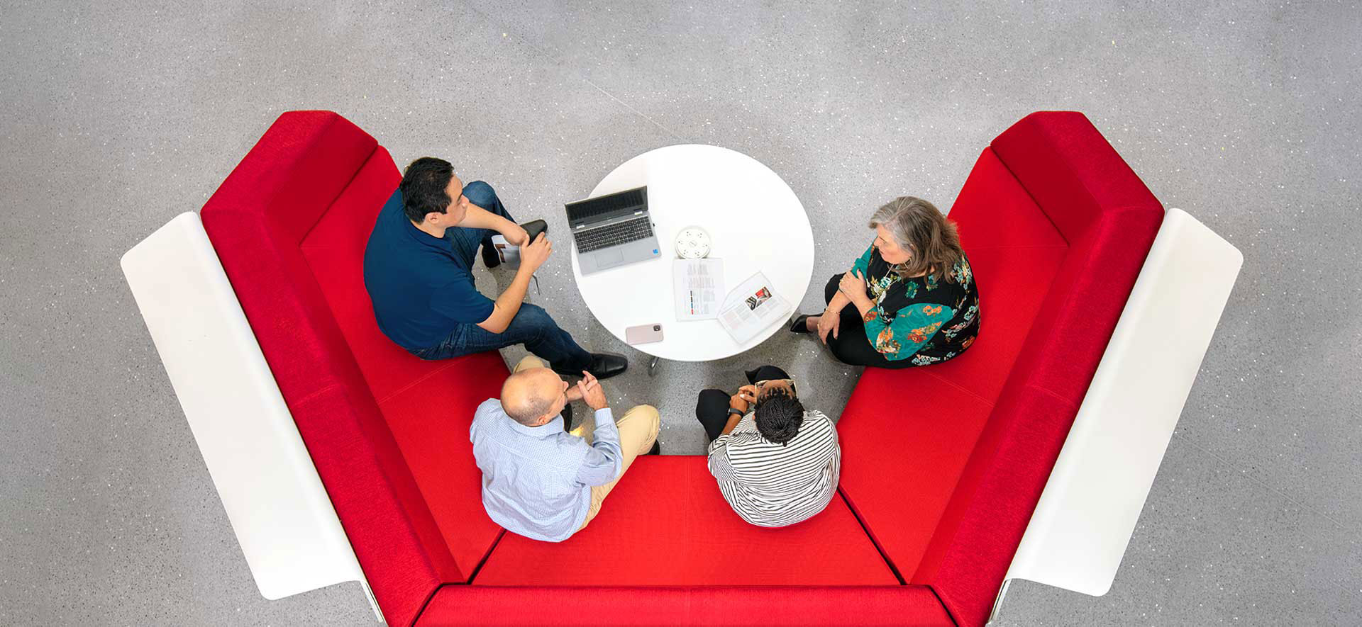 A group of RGA employees gather around a red couch