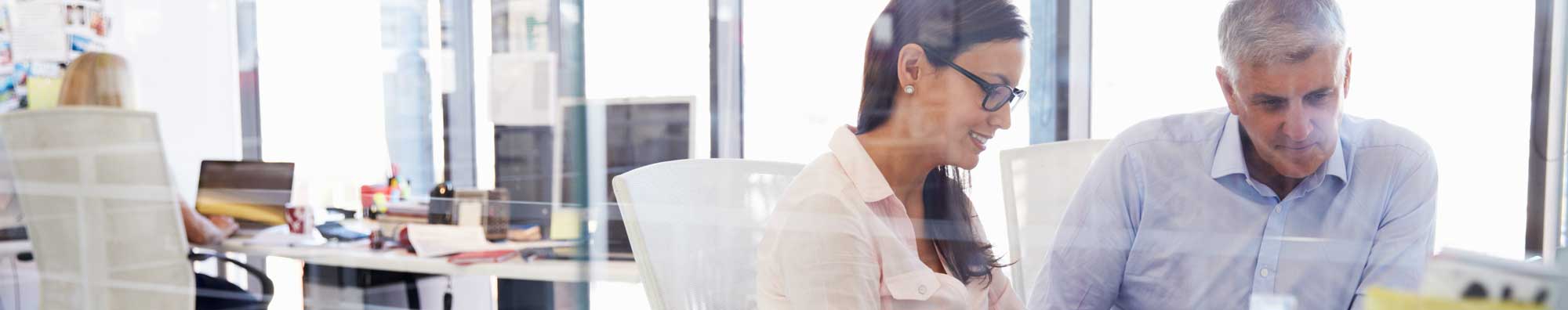 A group of claims analysts discuss a case in a glass walled office