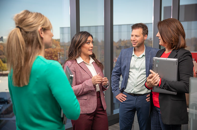 A group of Americas executives stand in a tight circle, talking against the backdrop of the RGA Headquarters