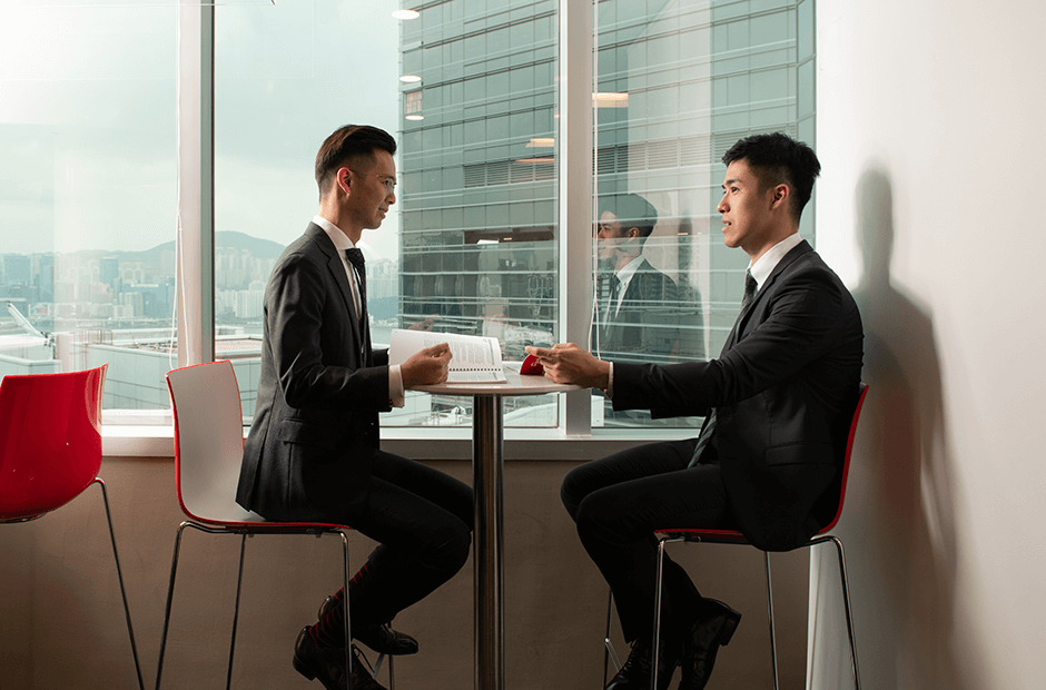 Two individuals meet at RGA Hong Kong with the bay in the background