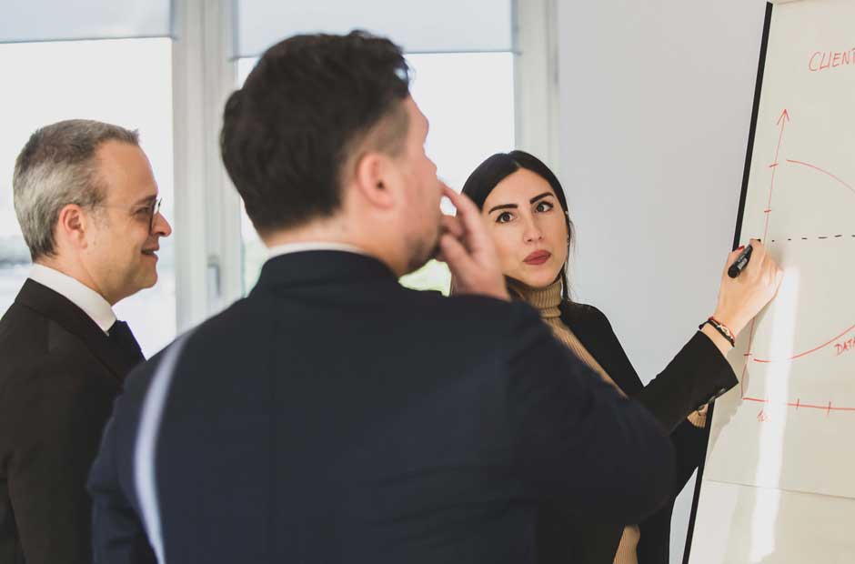 Members of the RGA Italy team gather around a whiteboard