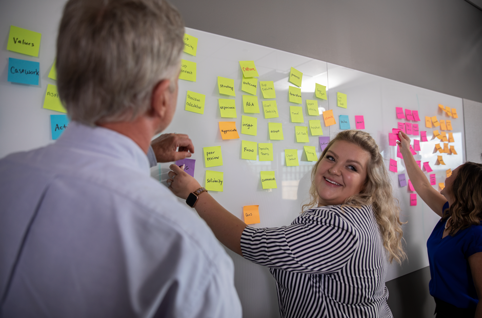 A group engages in a training exercise with sticky notes on a whiteboard