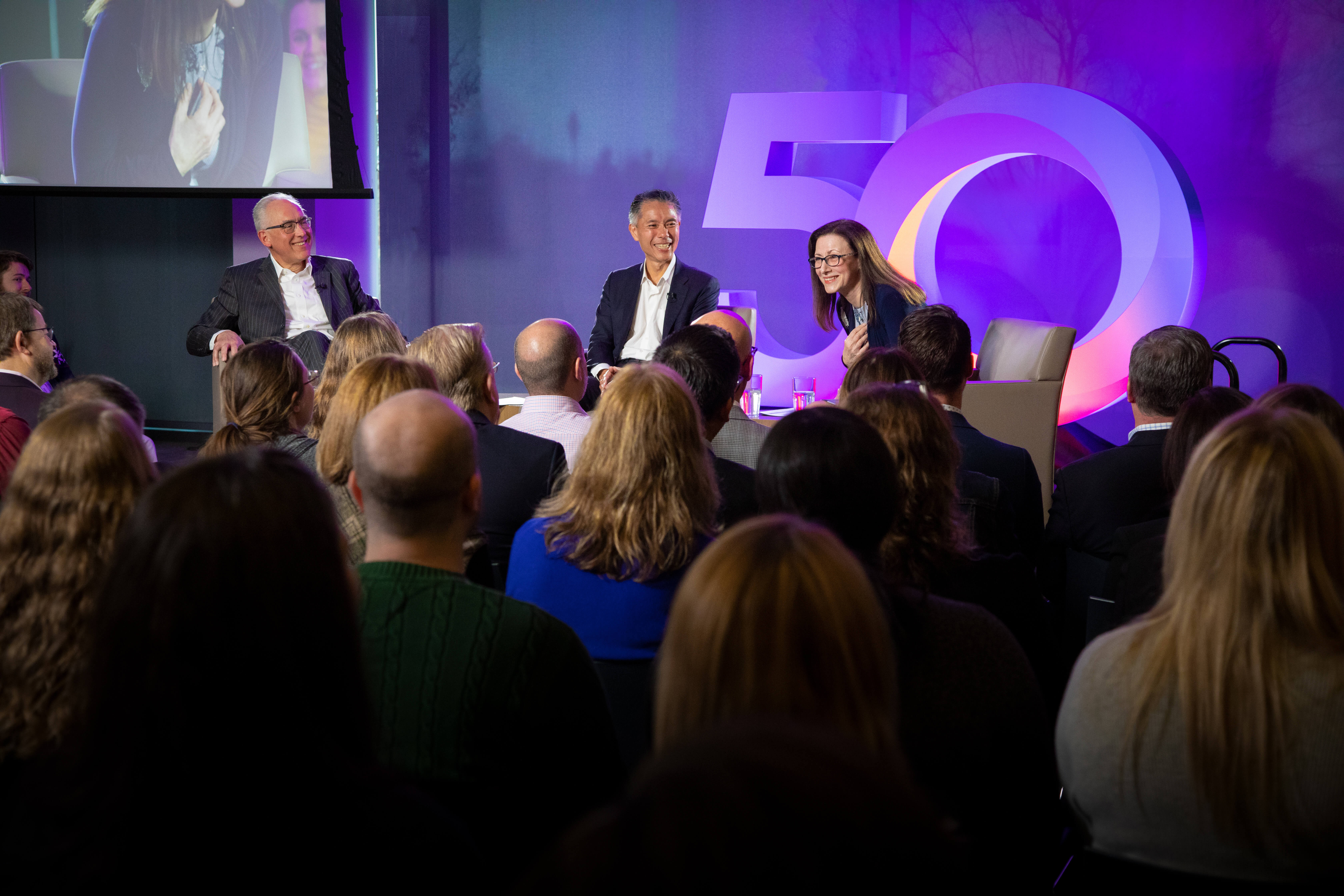 RGA leaders are seated on stage before a large crowd to celebrate 5oth anniversary