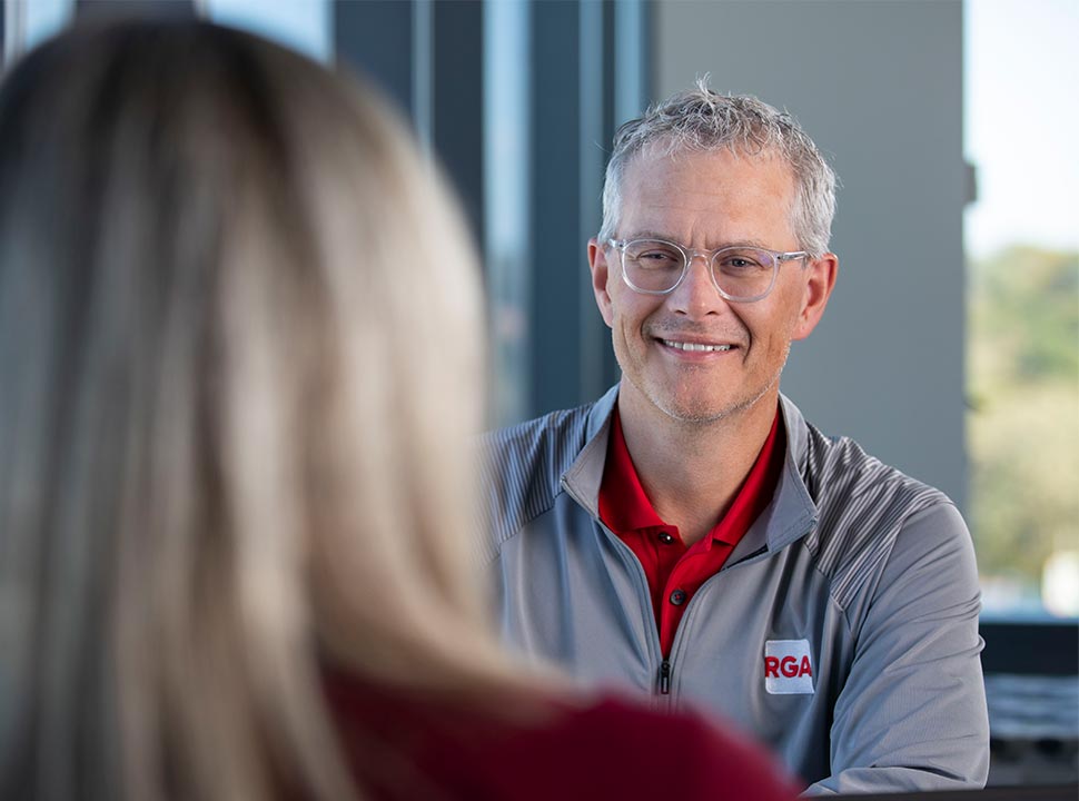 RGA Underwriting Employee Sitting at a Table in Discussion with a Colleague