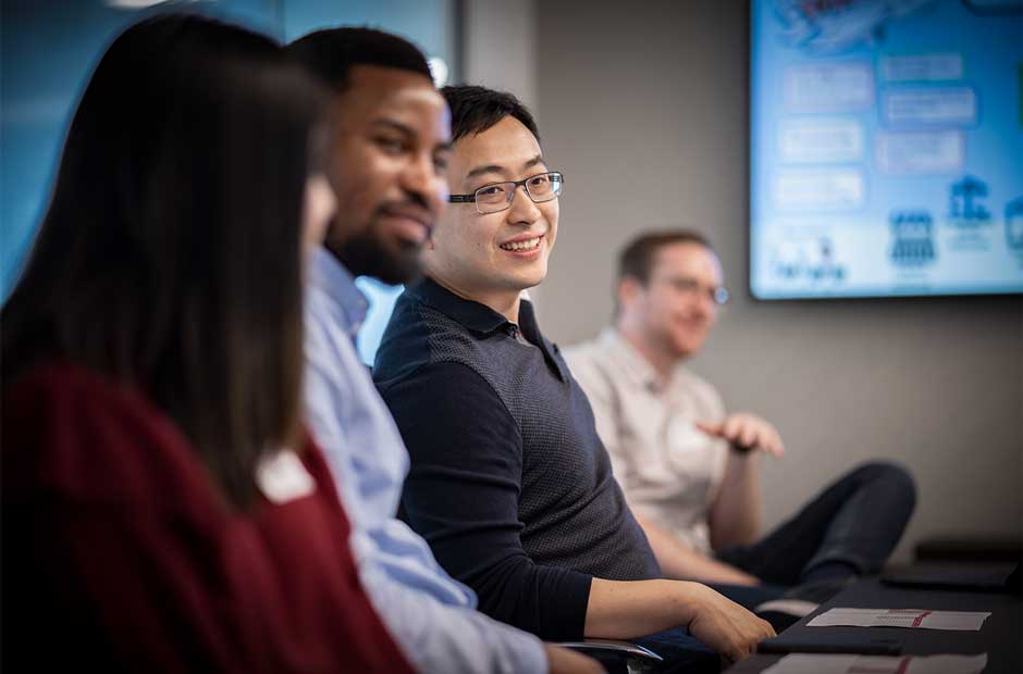 A diverse group of RGA UK employees laugh during a candid photo of a meeting