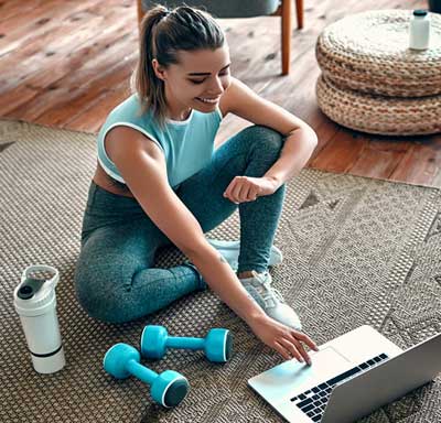 A woman in workout clothes checks technology after exercising