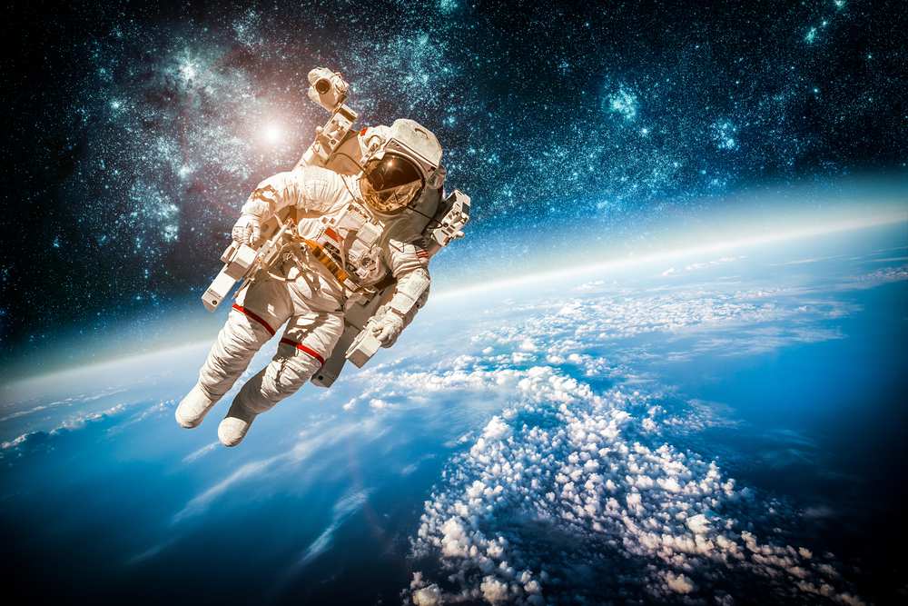 Astronaut floating above earth, illustrating a moonshot in underwriting and medicine