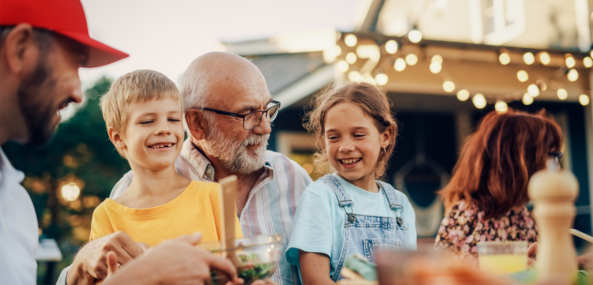 A grandfather sits with two smiling grandchildren on his lap