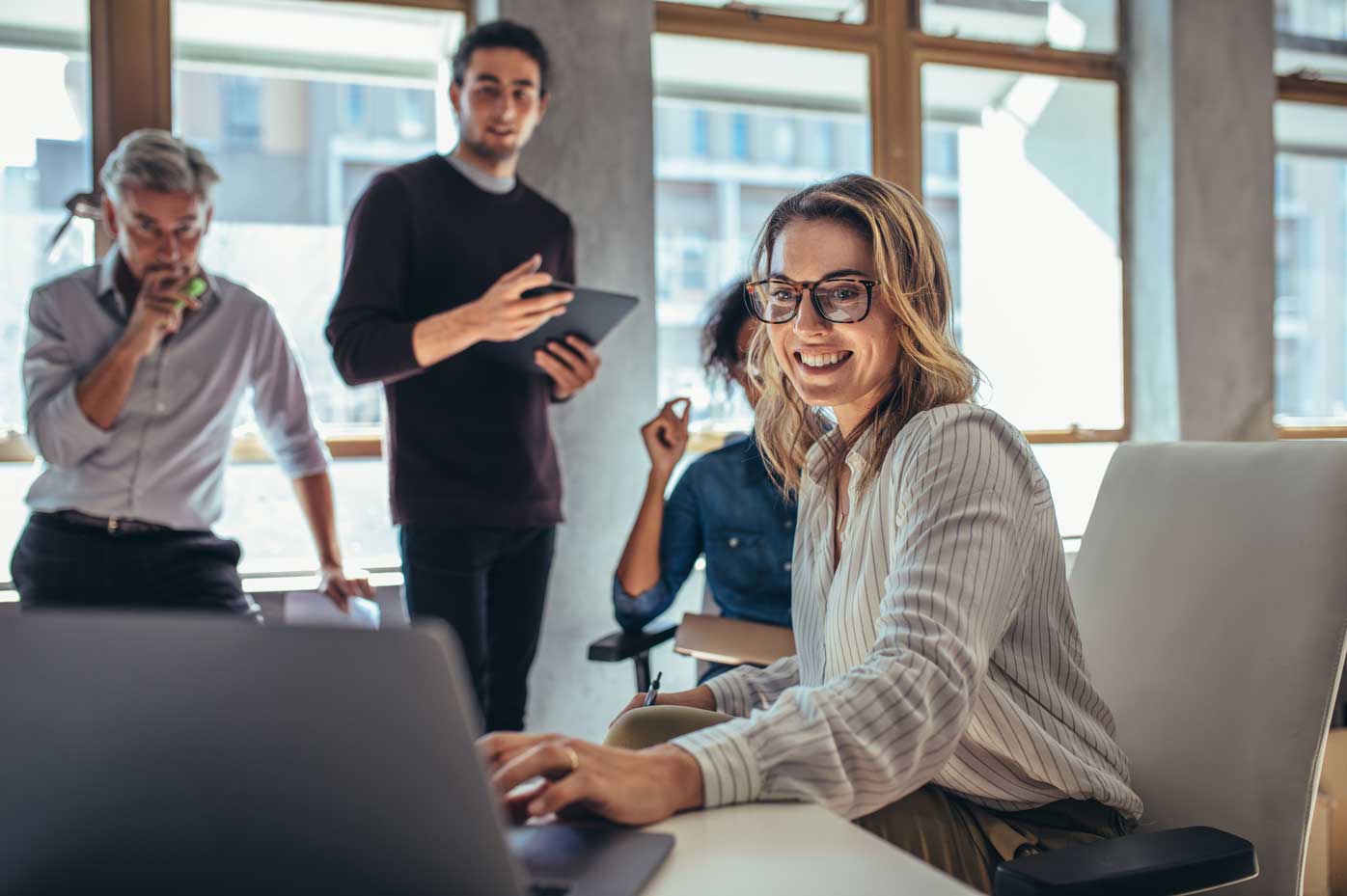 A group of actuaries grouped around a laptop discussing behavioral insight.