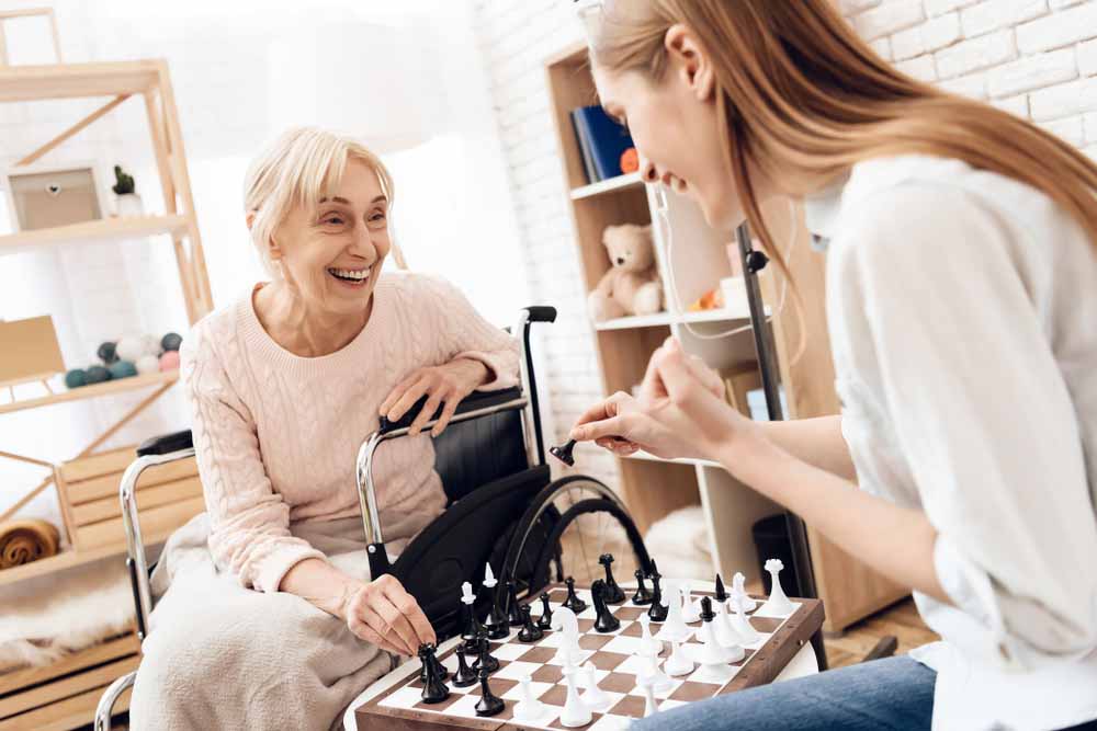 Caregiver image: elderly woman playing chess with younger woman
