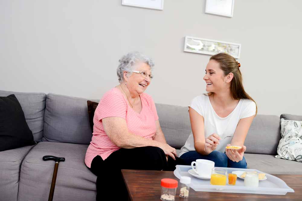 Elderly woman and young caregiver enjoy breakfast