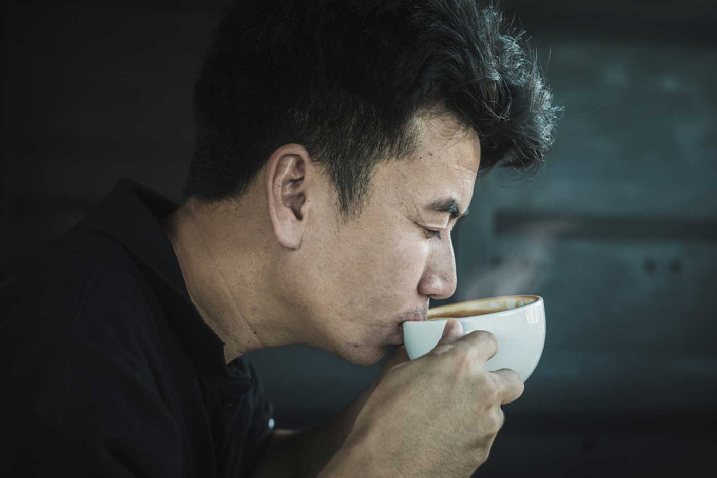 A man carefully sips a drink of coffee