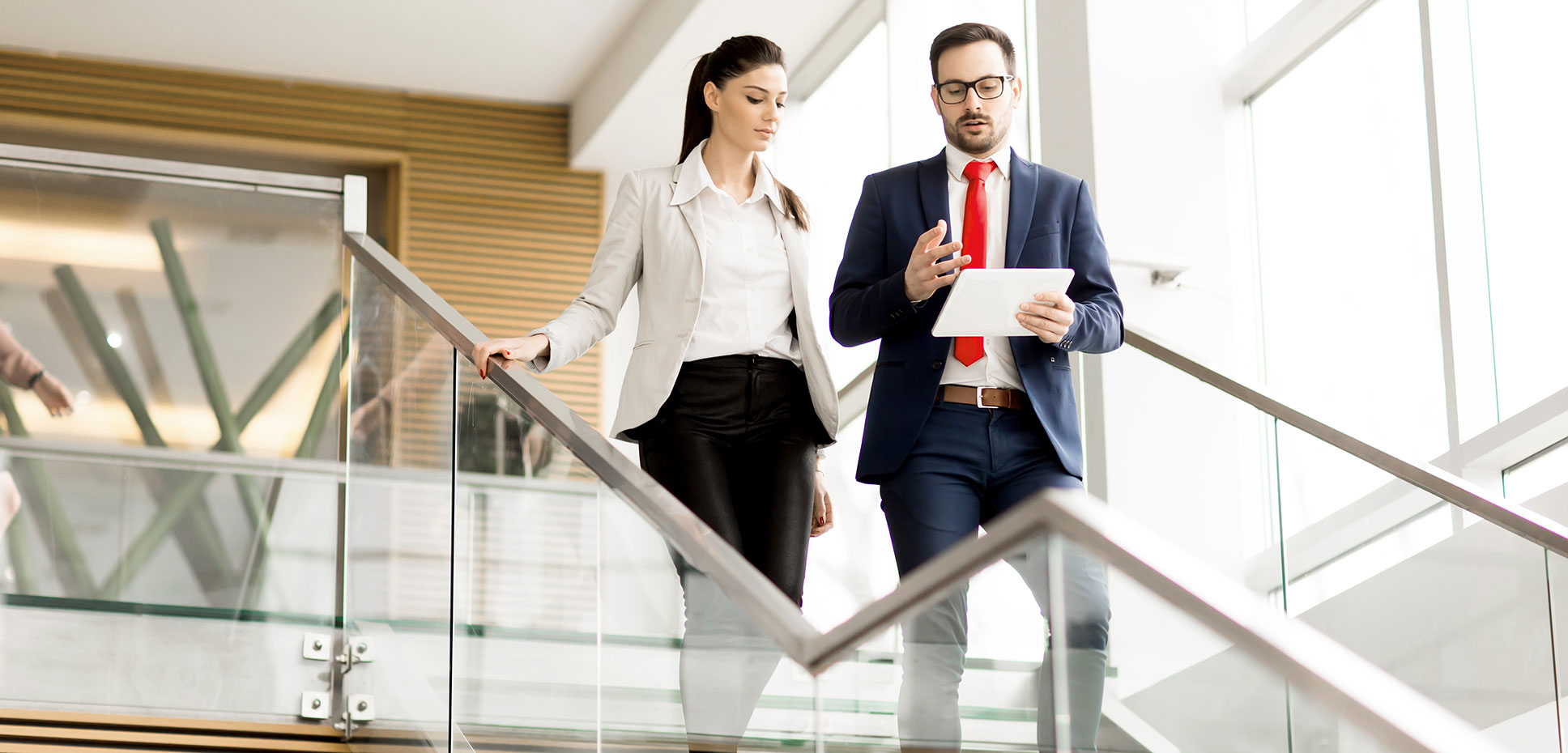 Man and woman in business attire descending office staircase