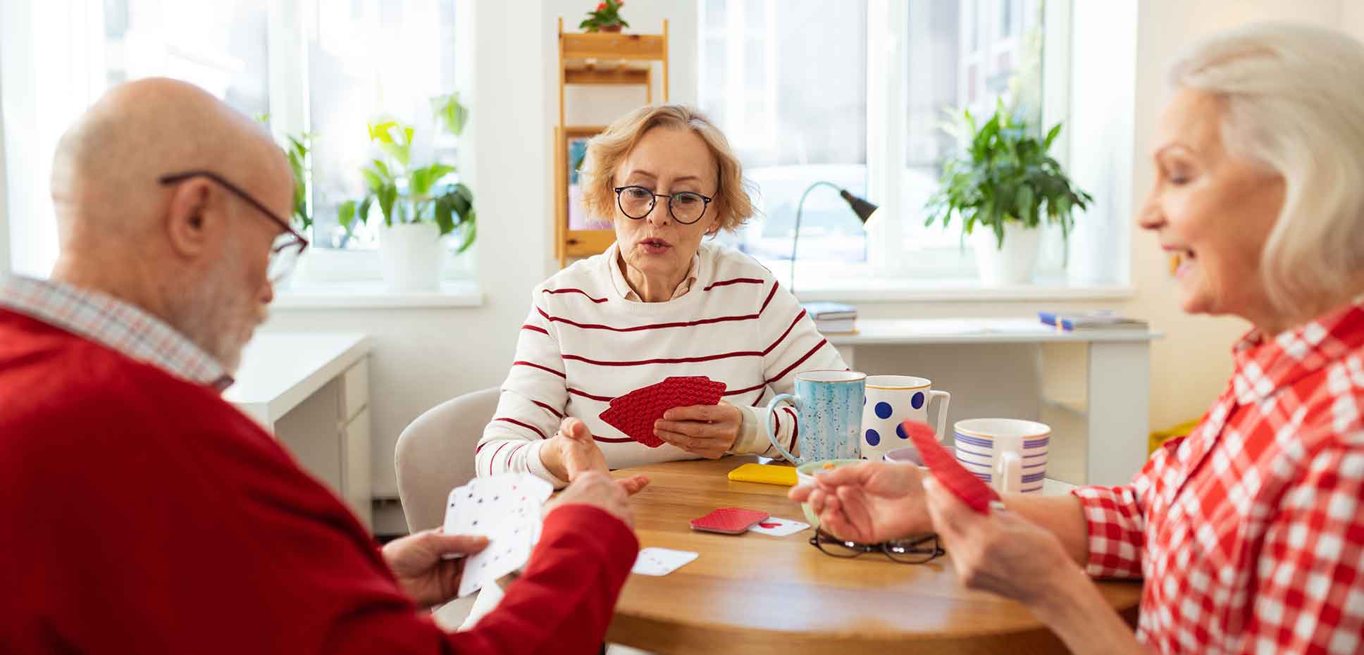 A group of pensioners play cards around the kitchen table