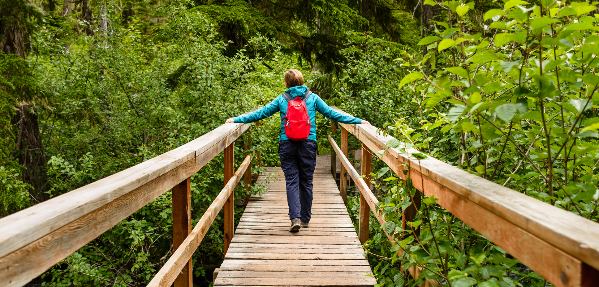 A woman crosses a wooden bridge while hiking in the woods