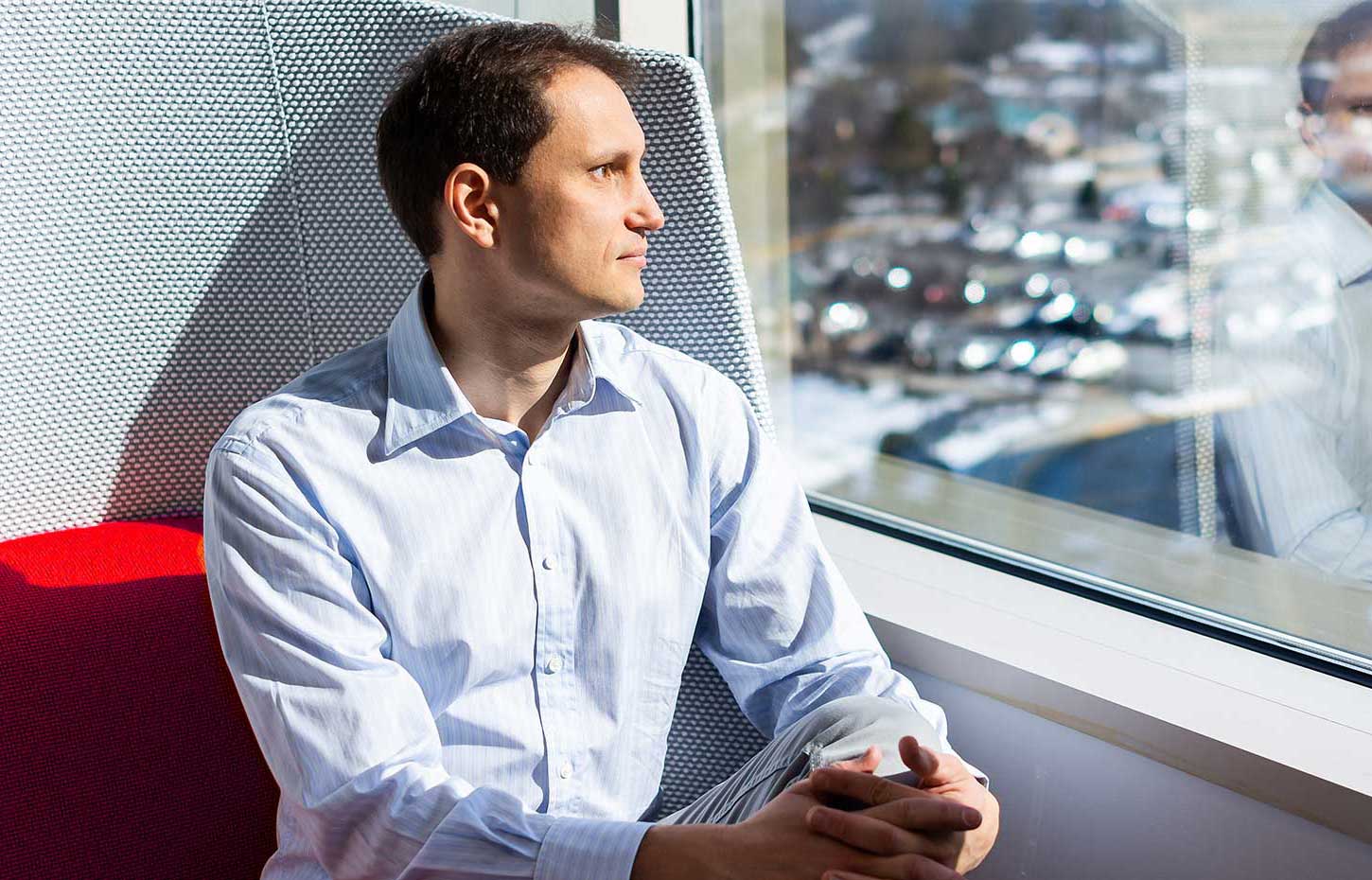 A man gazes out of the window, viewing the world beyond his office.