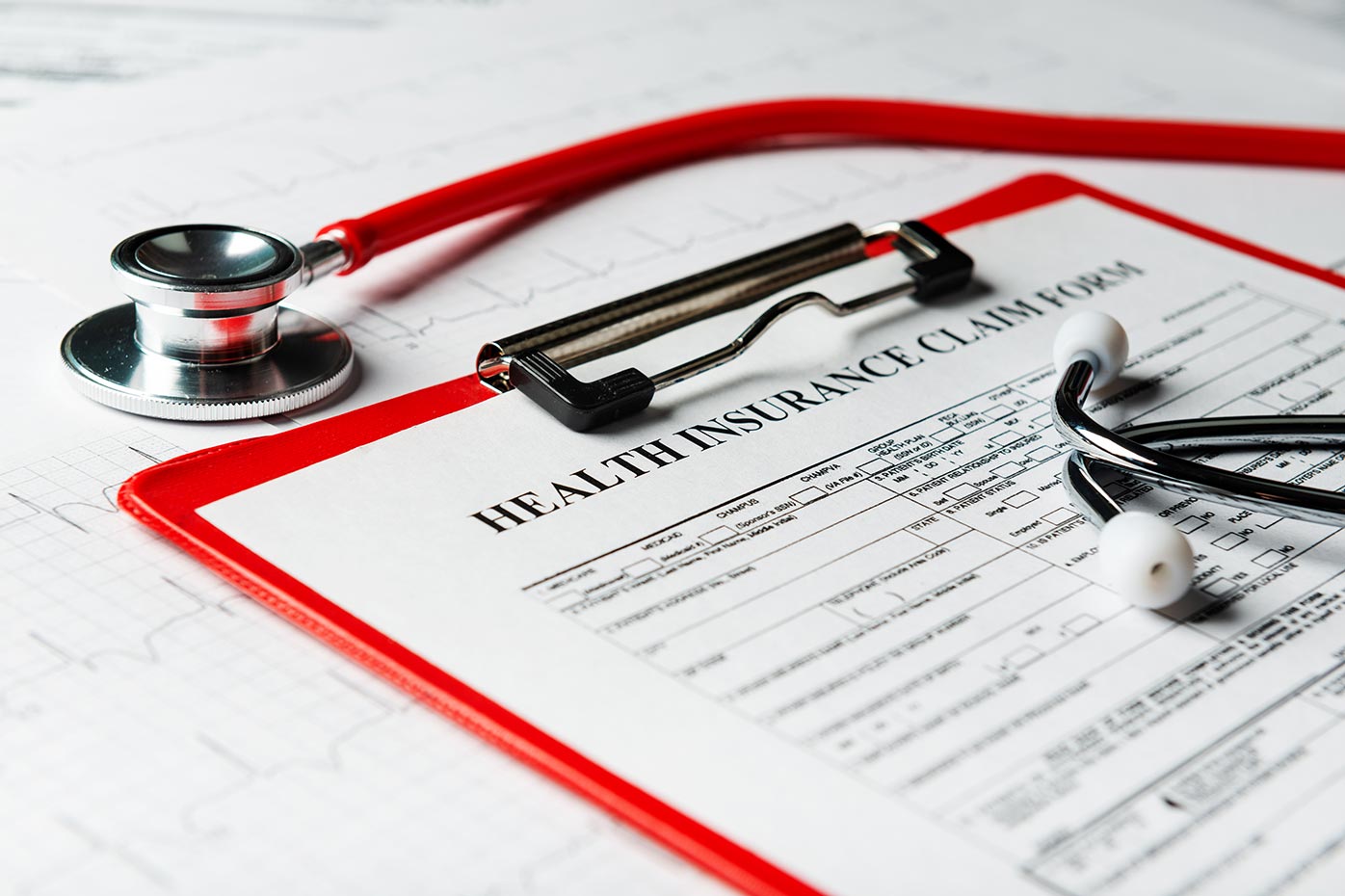 Stethoscope resting on clipboard with health insurance claim form