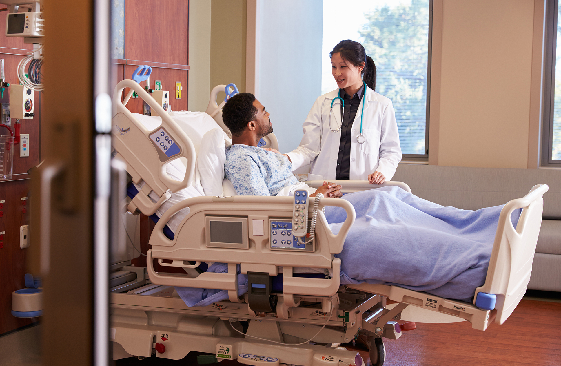 A man in a medical bed chats with an attending physician