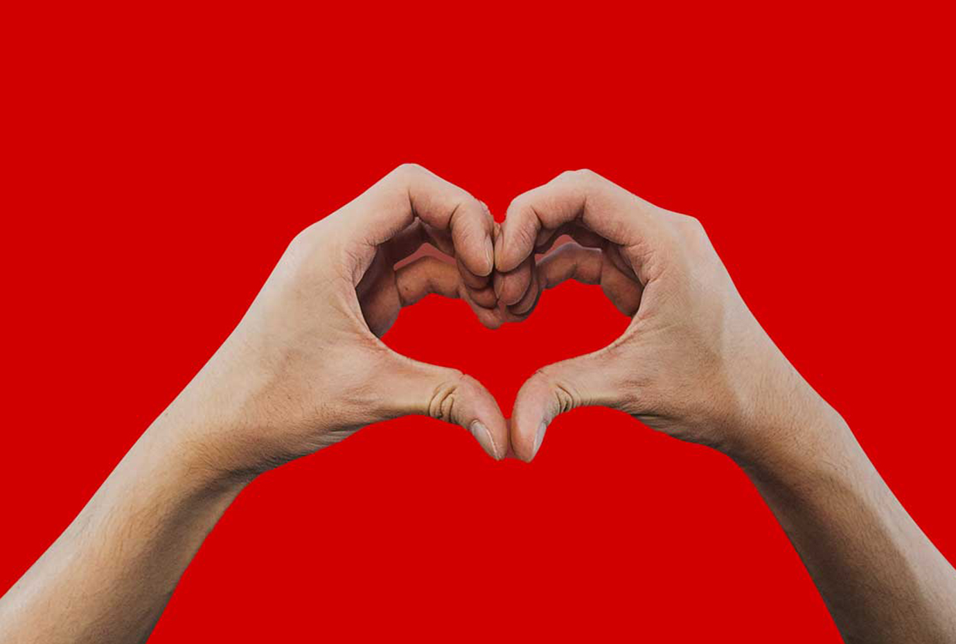 Hands making heart shape over red background