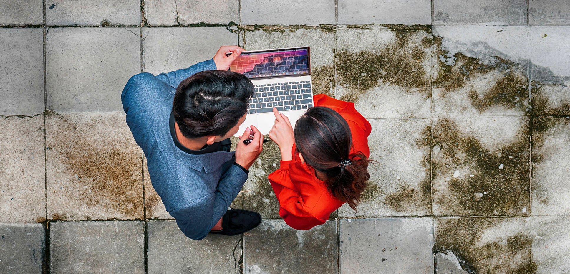 An overhead image of a businessman and woman holding a laptop