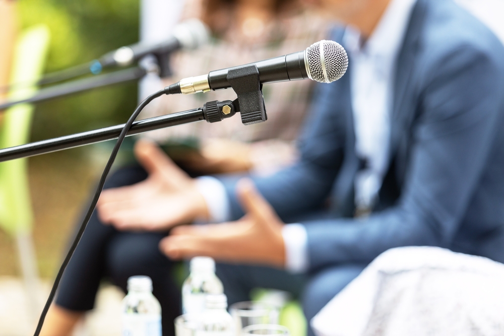 Group of out of focus businesspeople clustered around microphones