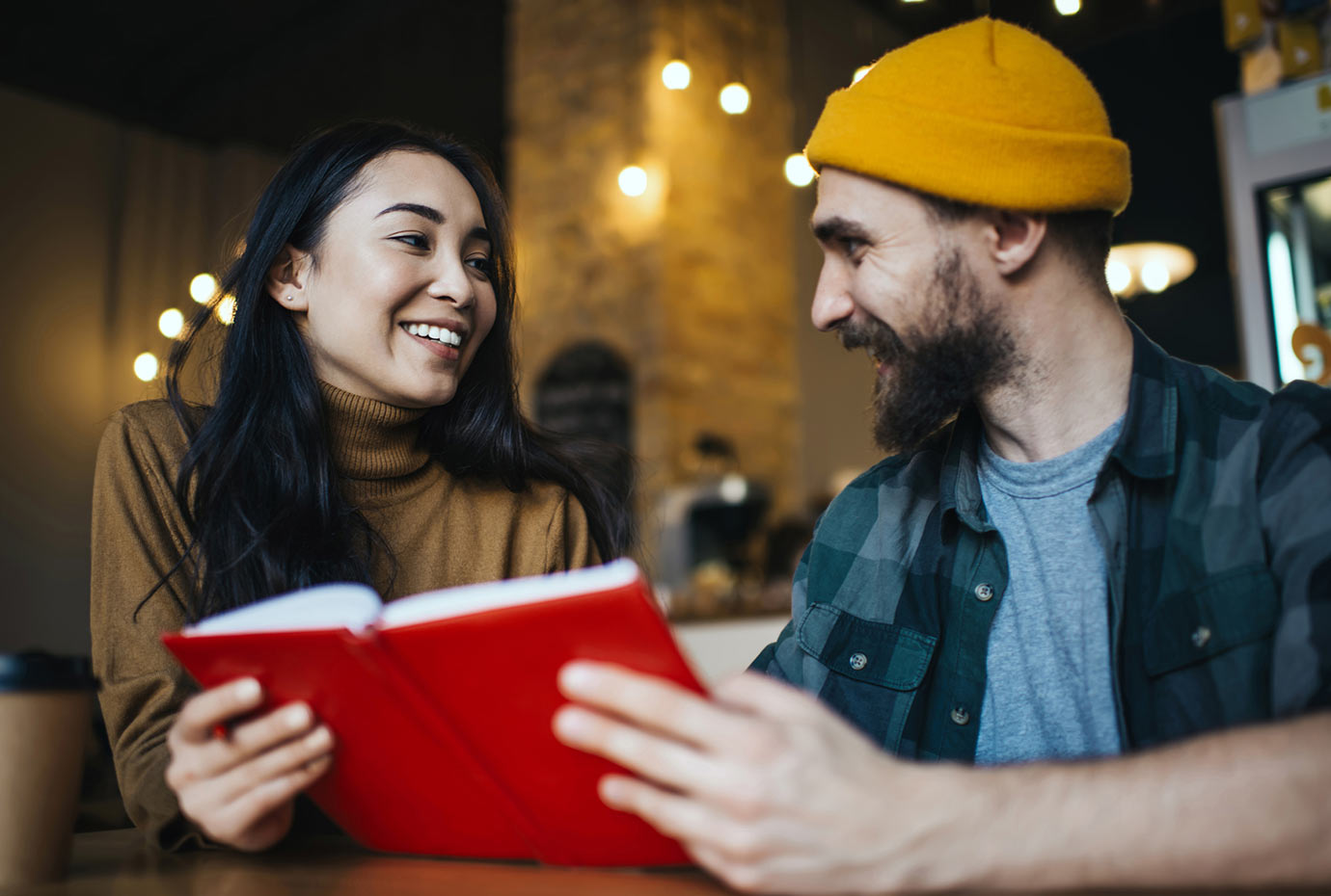 Man and woman reading a red book together