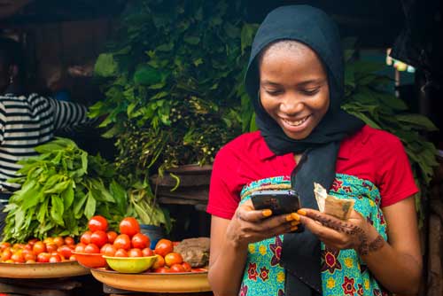 African woman using a mobile device to buy microinsurance