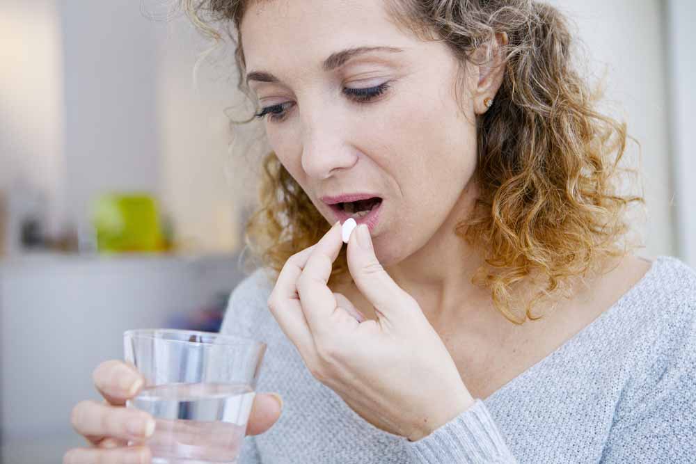 Opioid abuse with image clutching glass of water taking a pill