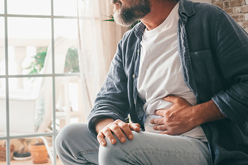 Man clutching stomach, in pain