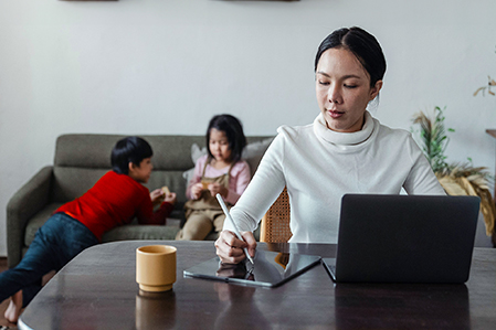 Woman on laptop with kids on the sofa