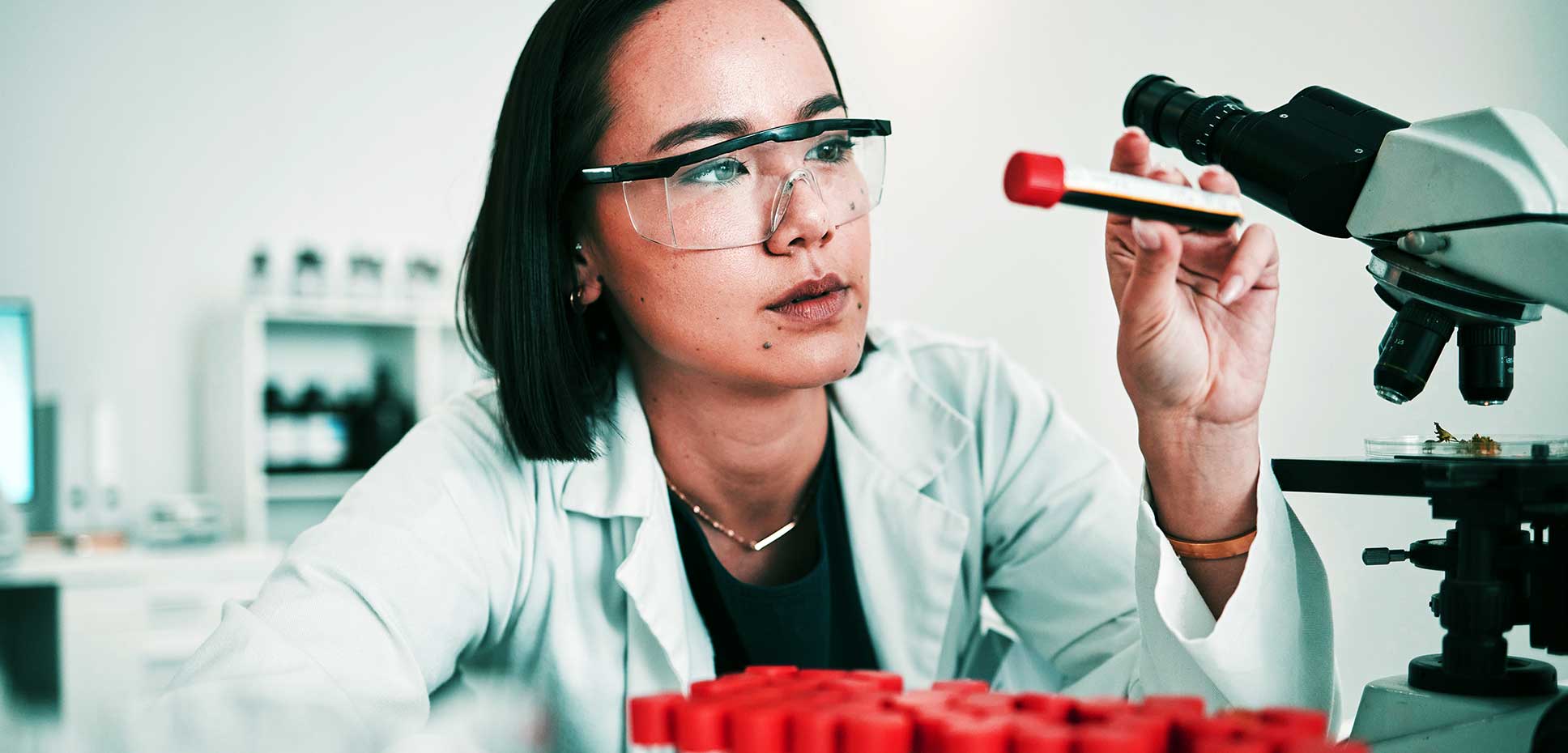 Woman in lab coat analyzing vial of blood