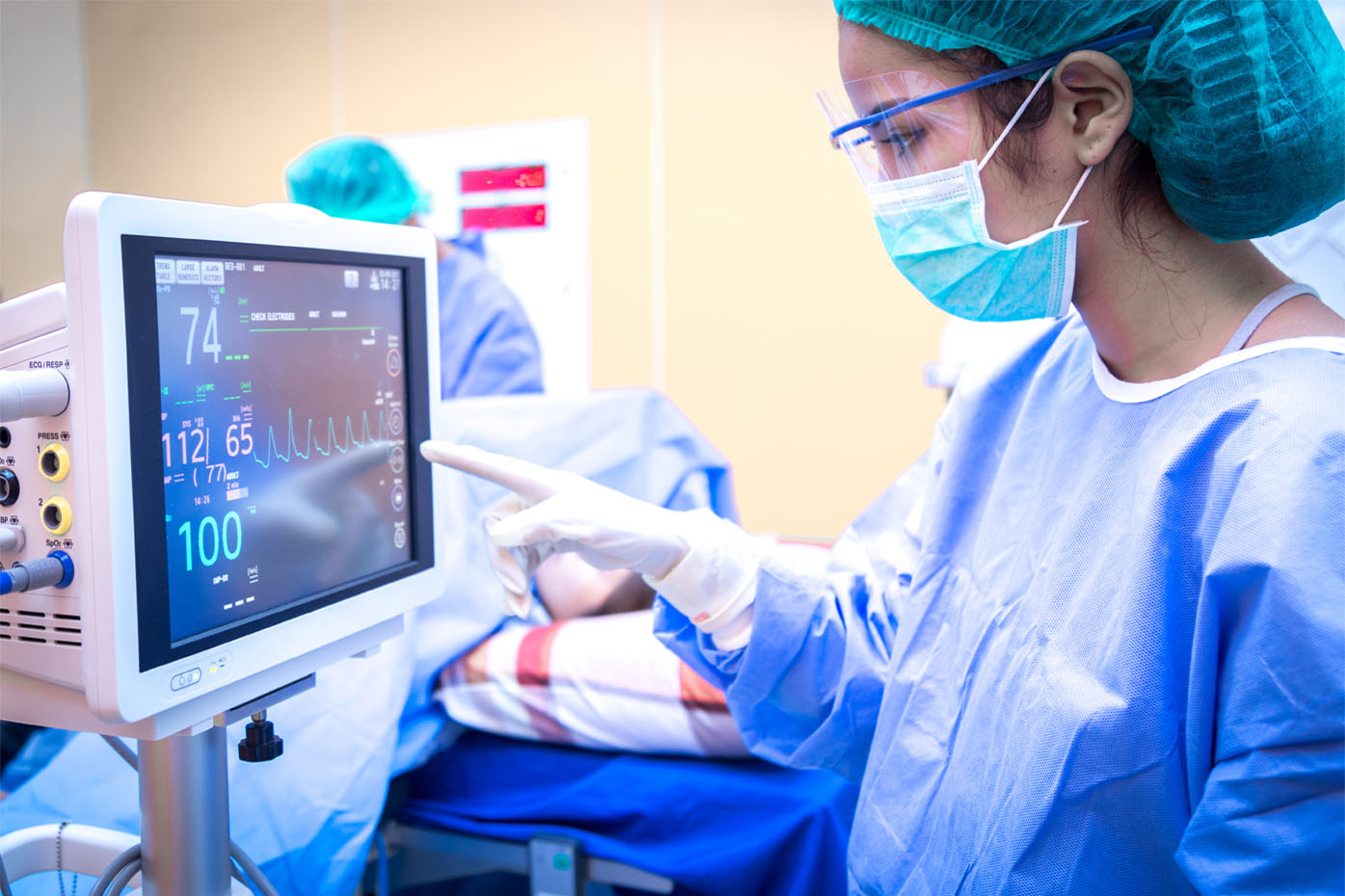 A female surgeon consults a patient monitoring device