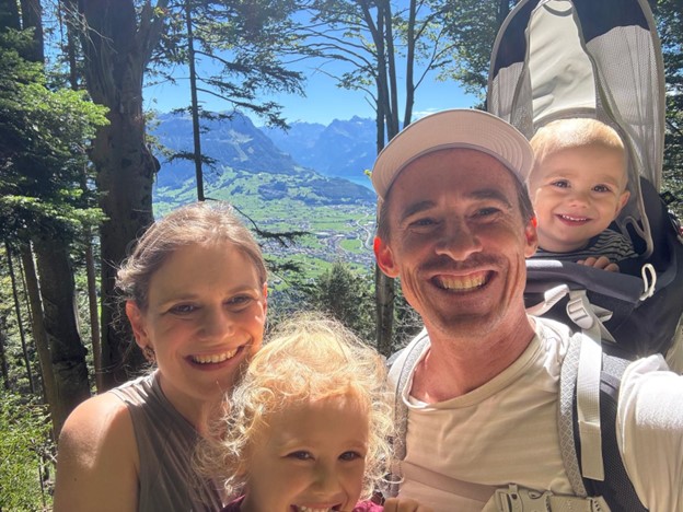 A man and woman and two small children pose together while hiking the Swiss alps