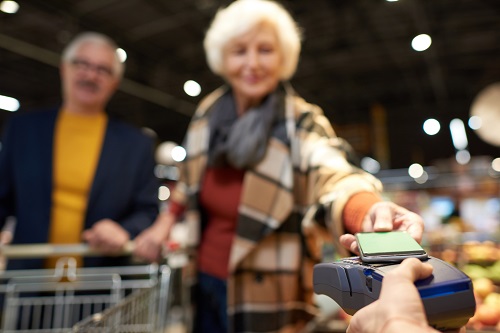 Image of elderly couple making purchase with smartphone