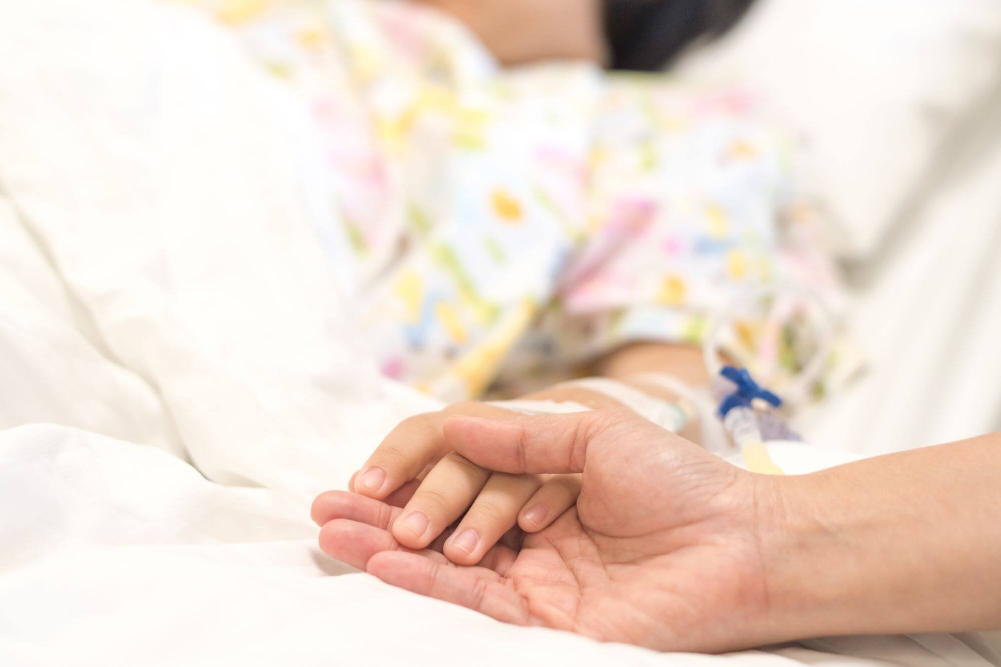 Holding hands with woman in hospital bed